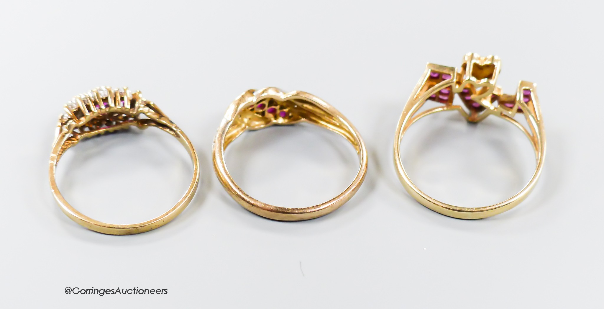 Three modern 9ct gold, ruby and diamond set dress rings including a 'Love' ring, size O, gross weight 5.7 grams.